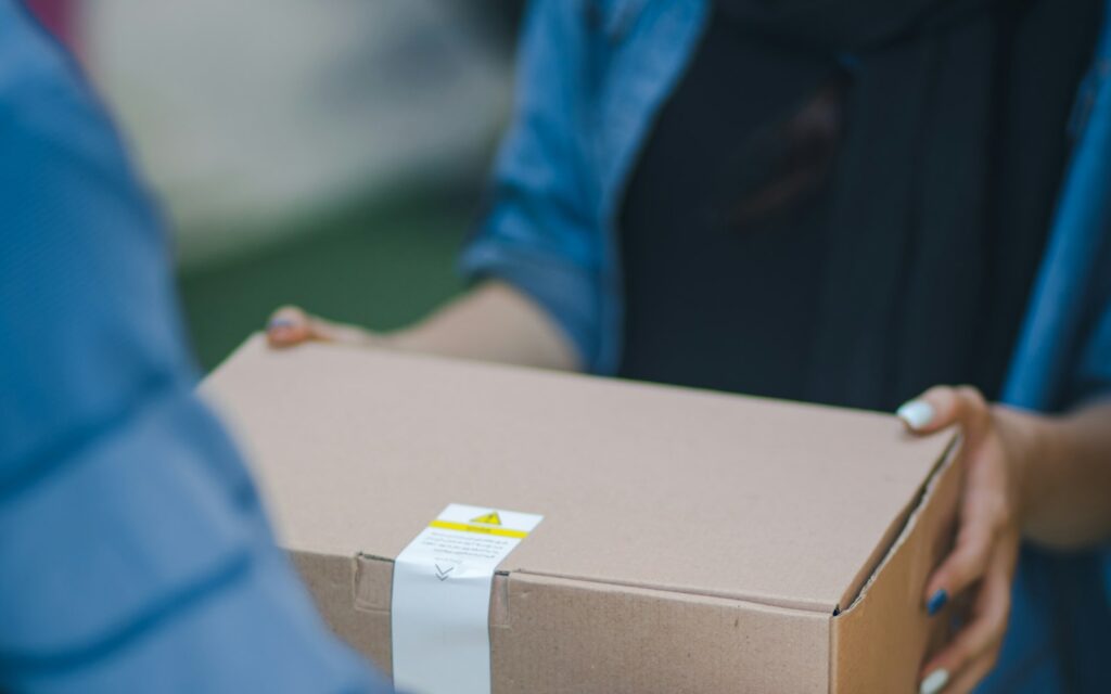 Repartidor entregando en mano una caja de cartón
