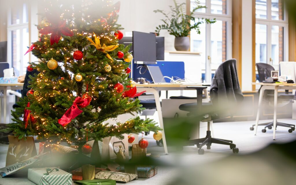 Oficina decorada con un árbol de Navidad entre los puestos de trabajo