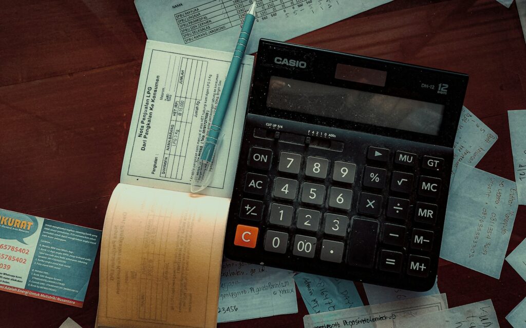 Calculadora, recibos y un bolígrafo sobre una mesa de madera