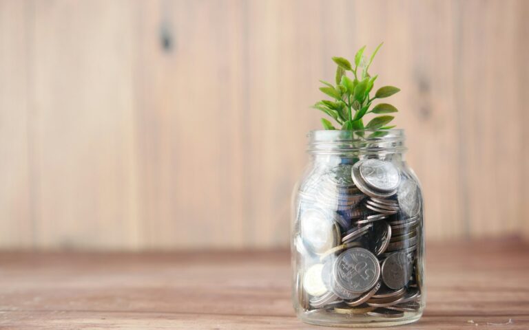 Tarro de cristal con monedas y una planta creciendo encima