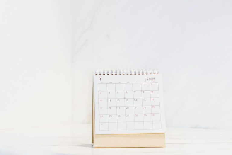 Un calendario de mesa con las fechas del mes sobre una superficie blanca