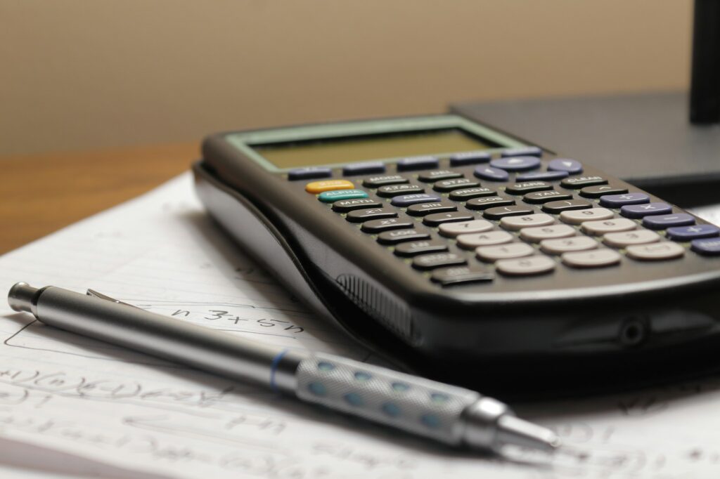 Una calculadora y un portaminas sobre una hoja con cuentas a mano