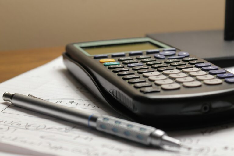 Una calculadora y un portaminas sobre una hoja con cuentas a mano