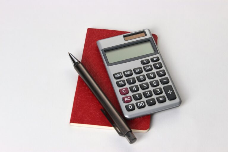 Una calculadora y un bolígrafo sobre una libreta roja