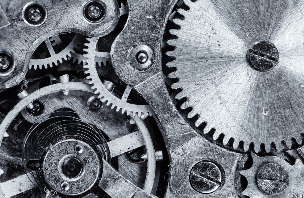 Primer plano en blanco y negro de los engranajes metálicos de un mecanismo de reloj