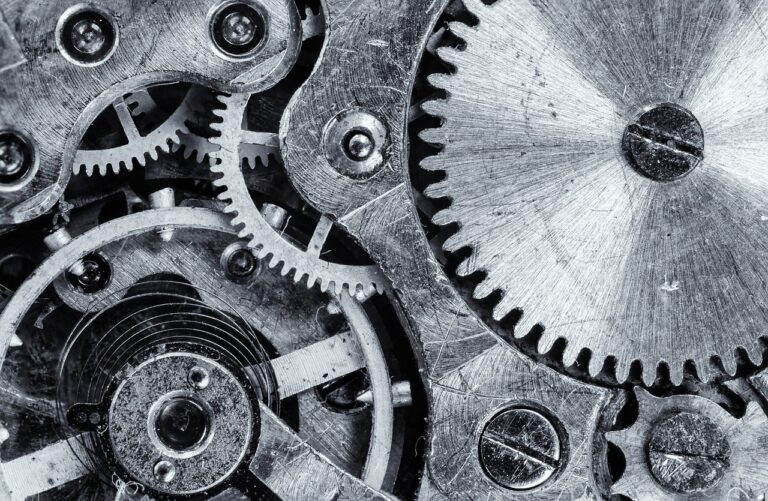 Primer plano en blanco y negro de los engranajes metálicos de un mecanismo de reloj